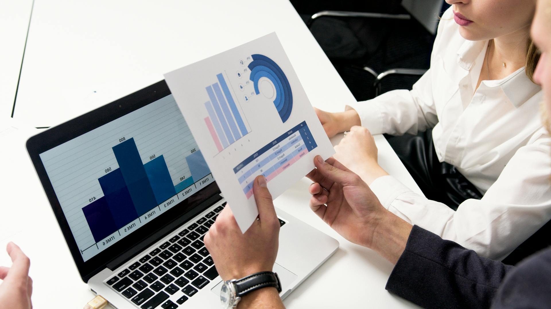 Business professionals analyzing graphs on a laptop, focused on a Due Diligence Checklist.